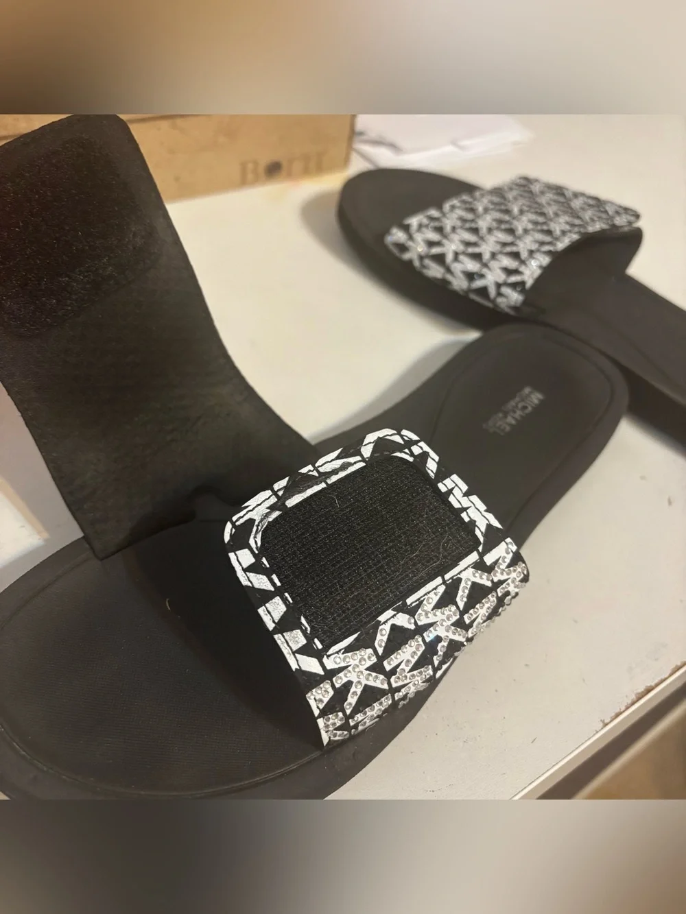 Michael Kors black & white slides featuring a signature logo print on the strap.